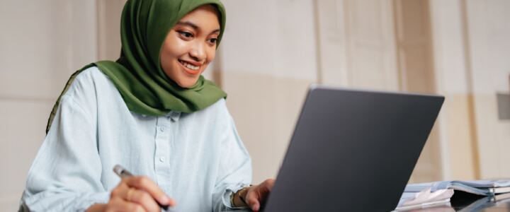 Student smiling at her laptop while reviewing PTE practice questions